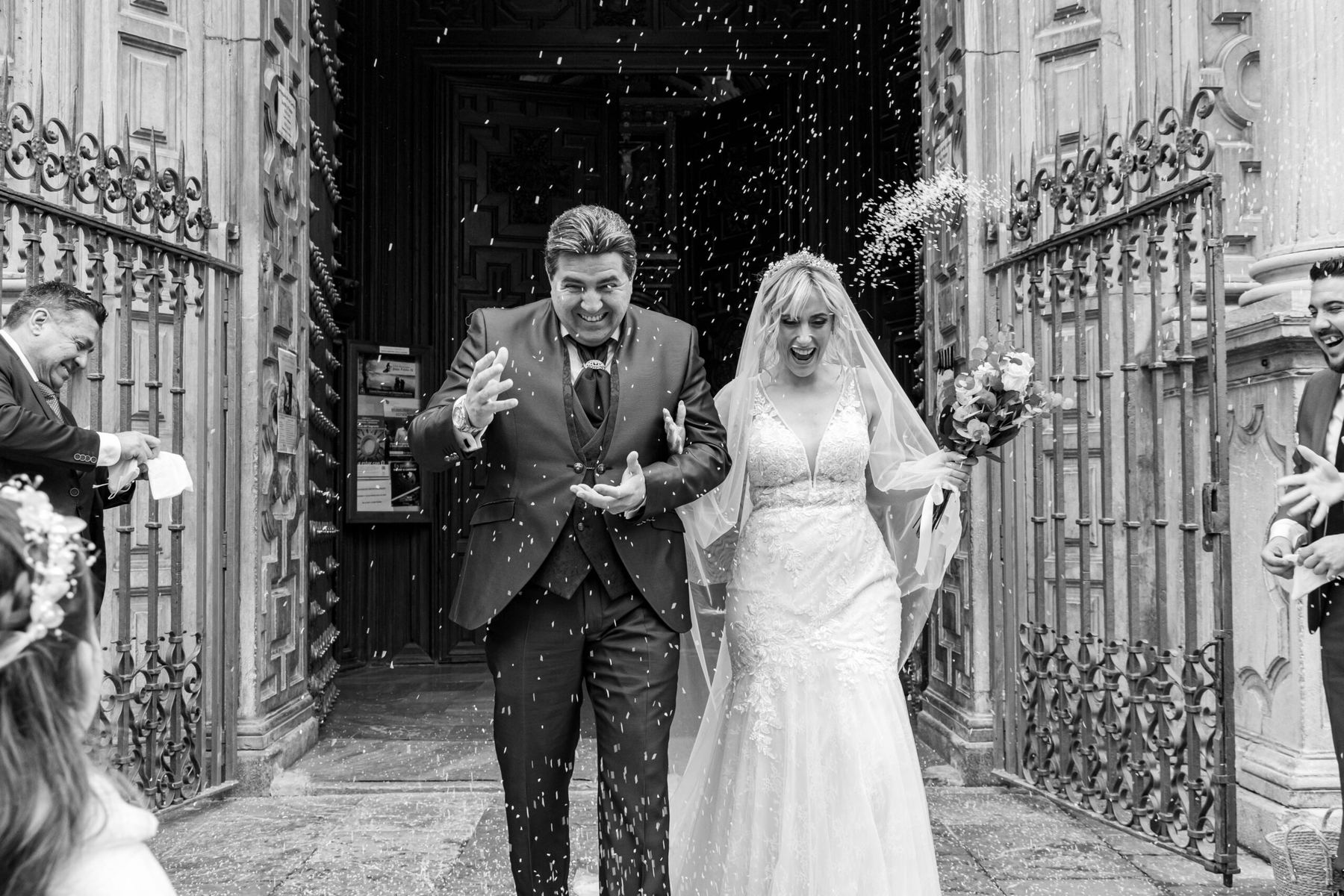 Salida de los novios de la iglesia entre arroz, en blanco y negro